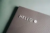 Close-up of a minimalist letter board with 'Hello' text and smiley face on a green backdrop.